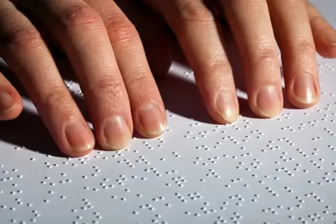 dita che leggono una riga di testo in braille