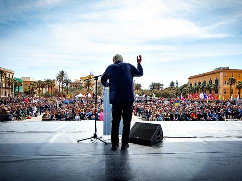 fotografia di don Ciotti ripreso da dietro su palco e folla davanti