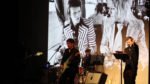 attori in scena che suonano e leggono, sullo sfondo immagini di Bowie